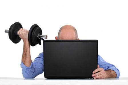 Photo of a business man doing a curl at his computer