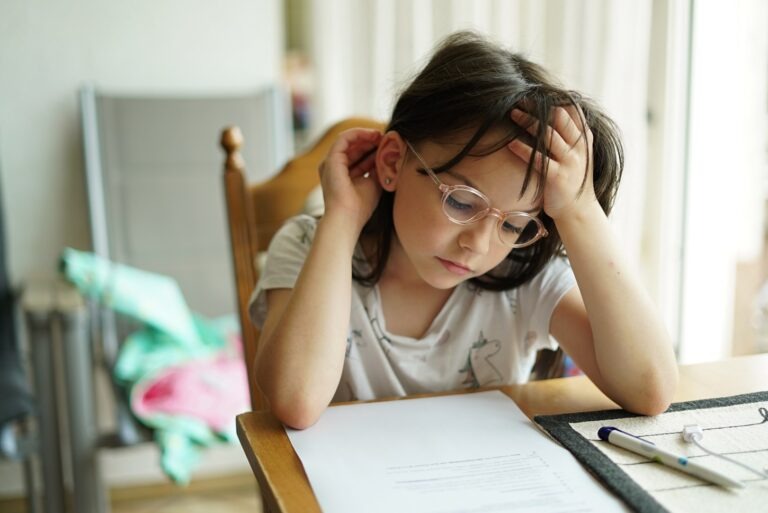 Little girl with glasses looks stressed over school papers