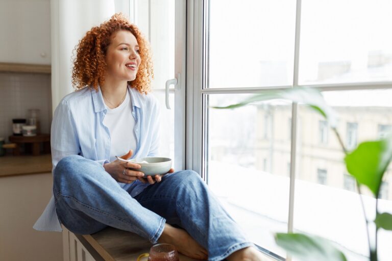 Woman with red curly hair sitting by window