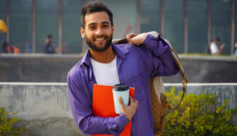 young man with backpack on one shoulder and holding a coffee cup and folder