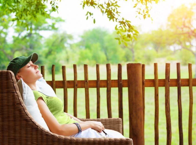 Relaxed woman on a patio chair overlooking grass