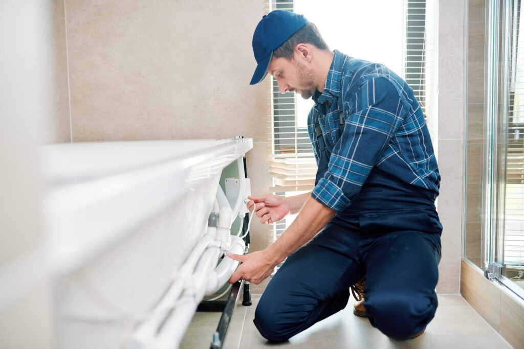 Plumber at a bathtub with a wrench