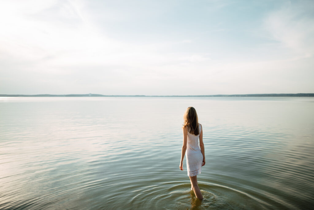 Woman standing in body of water looking out