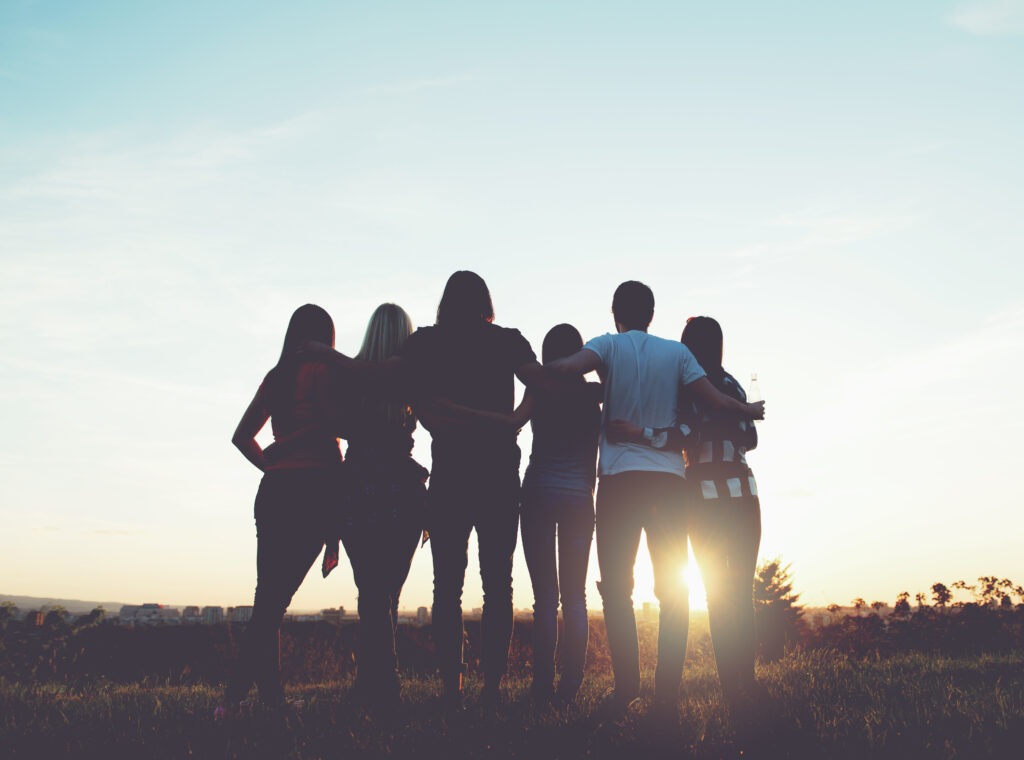 Group of people in silhouette facing the sun