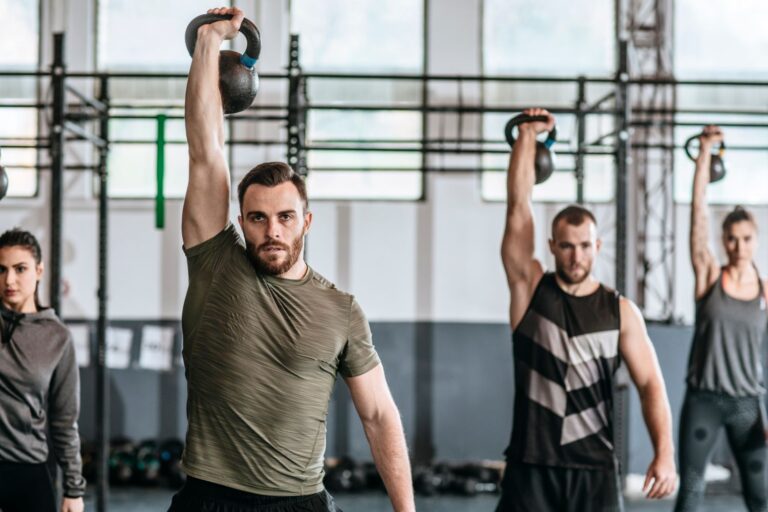 Group of men lifting a weight above their head in crossfit class